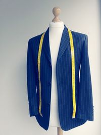 Blue jacket and measuring tape on dressmakers model against white wall