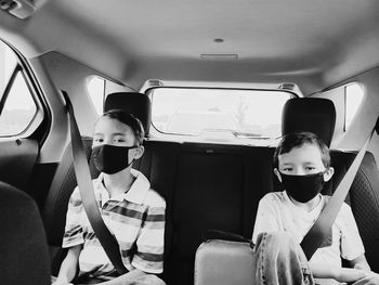 Portrait of cute kids wearing flu mask sitting in car