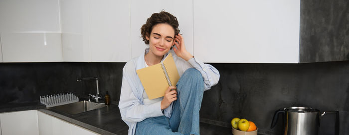 Portrait of young woman standing against wall