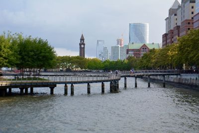 Bridge over river by buildings against sky