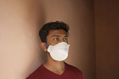 Young man with mask against wall