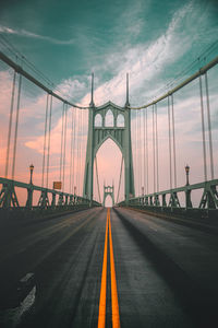 Symmetrical view of bridge against sky during sunset