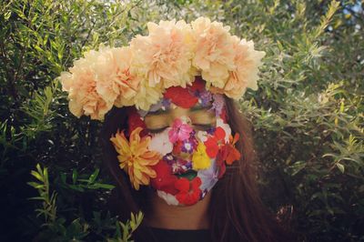 Close-up of teenager wearing flowers against plants