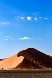 Landscape and sand dune against blue sky
