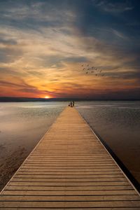 Pier over sea against sky during sunset