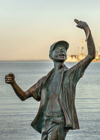 Statue by sea against sky during sunset