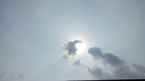 Low angle view of sunlight streaming through clouds