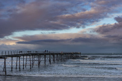 Pier over sea against sky during sunset