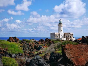 Lighthouse by sea against sky