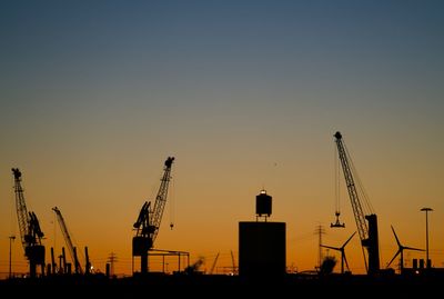 Silhouette of construction site against clear sky during sunset