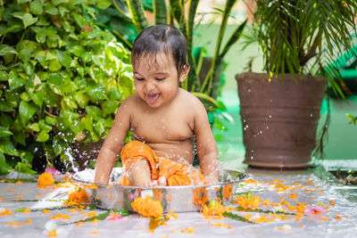 Cute toddler baby boy bathing in decorated bathtub at outdoor from unique perspective