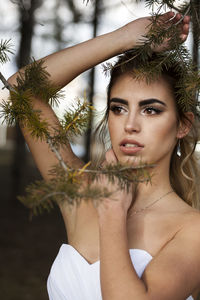 Portrait of beautiful young woman against blurred trees