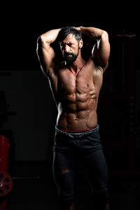 Midsection of man with arms crossed standing against black background