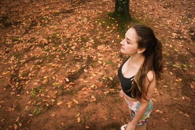 High angle view of young woman standing in forest during autumn