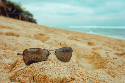 Close-up of sunglasses on beach