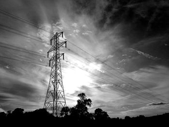 Low angle view of electricity pylon against cloudy sky