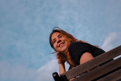 Low angle portrait of young woman against sky