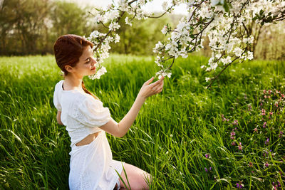 Side view of young woman standing on grassy field