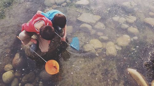 High angle view of boys fishing on lake with net