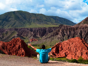 Rear view of man siting on land against mountain