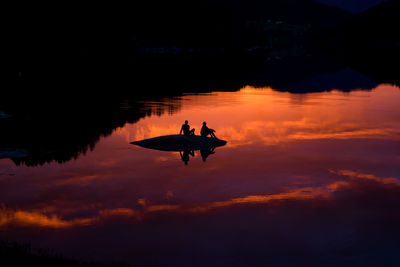 Silhouette boat on lake against sky at night
