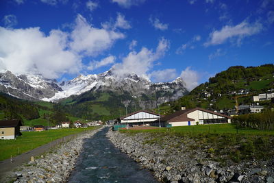 Road amidst buildings and mountains against sky