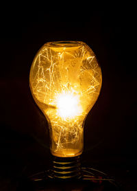 Close-up of illuminated light bulb against black background