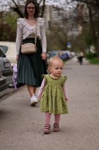 Little baby girl and her mother walking down the street