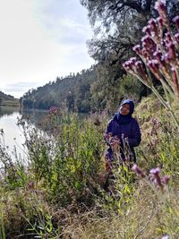Young man on rock against sky