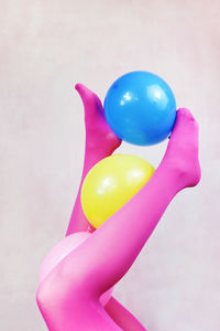 Close-up of hand holding balloons against white background