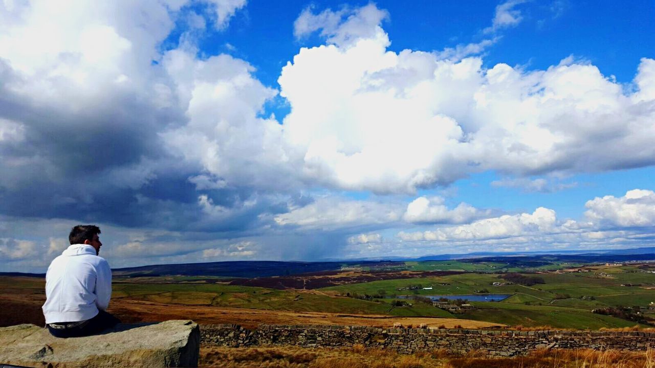 rear view, landscape, cloud - sky, sky, men, tranquility, beauty in nature, field, rural scene, scenics, tranquil scene, agriculture, casual clothing, nature, day, getting away from it all, outdoors, cloudscape, dramatic sky, horizon over land, solitude, cloudy, distant, mountain, non-urban scene, majestic