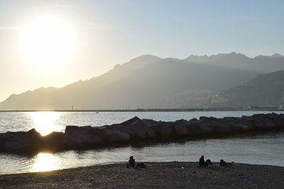 People on beach by mountains against sky