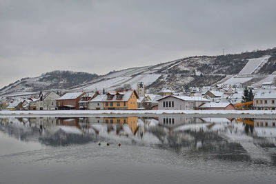 Buildings by mountain against sky during winter