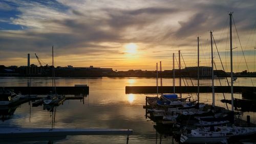 Boats at harbor against cloudy sky