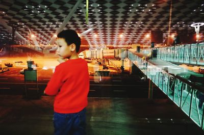 Boy standing by illuminated lights at night