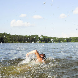 Rear view of man swimming in lake mackintosh against sky