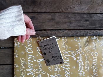 Cropped hand of woman with greeting card and present on table