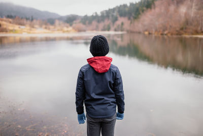 Rear view of man standing in lake during winter