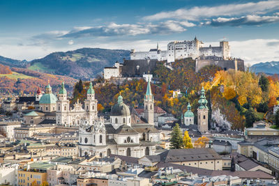 Townscape by mountains against cloudy sky