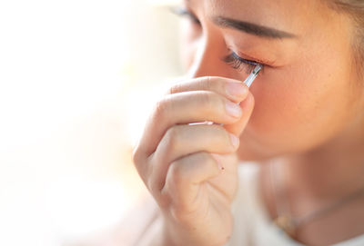 Female hand holding the eyelash and preparing to attach it to her eye.