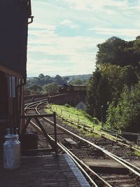 Railway tracks by trees against sky