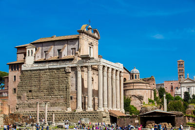 Tourists visiting the roman forum and the temple of antoninus and faustina at the roman forum