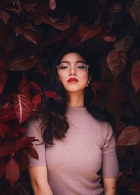 Portrait of young woman standing with leaves
