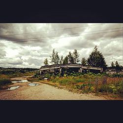 Road passing through field against cloudy sky