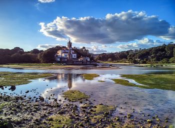 Reflection of church in lake against cloudy sky