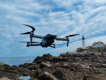 Low angle view of airplane flying over rocks against sky