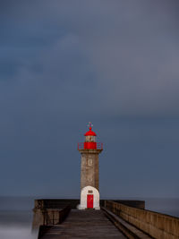 Lighthouse by sea against sky