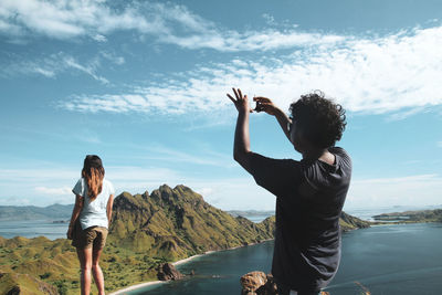 Rear view of women standing on mountain against sky