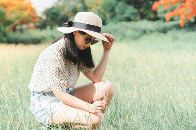 Young woman wearing hat sitting on field