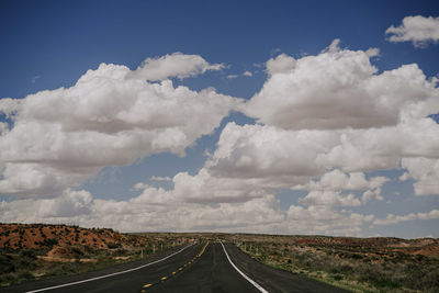 Road passing through landscape against cloudy sky